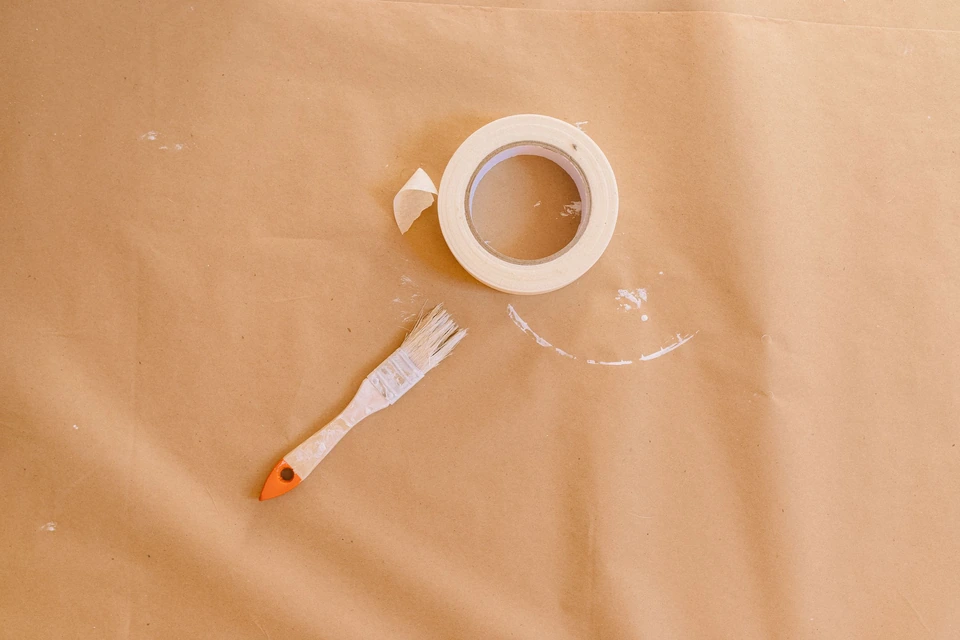 Rol schilderstape en een kwast op afdekpapier, klaar voor het verfwerk